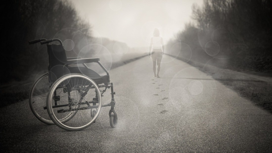 Frau steht aus Rollstuhl auf